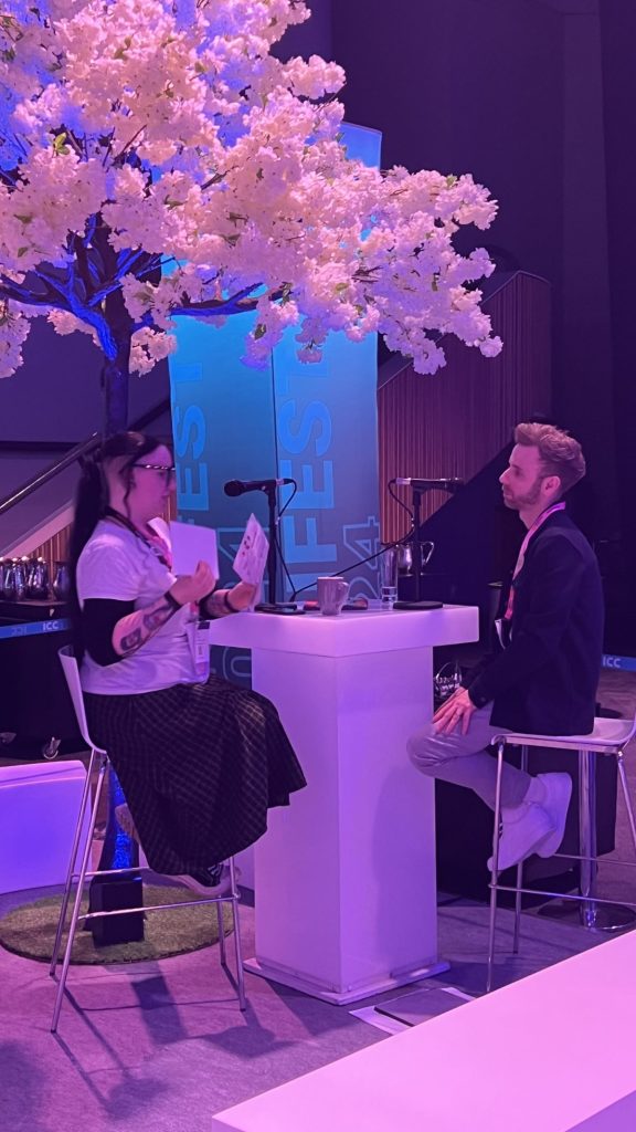 Chloe Hynes and PhilWhitehead sat down at a stand, talking on a podcast at Digifest 2024