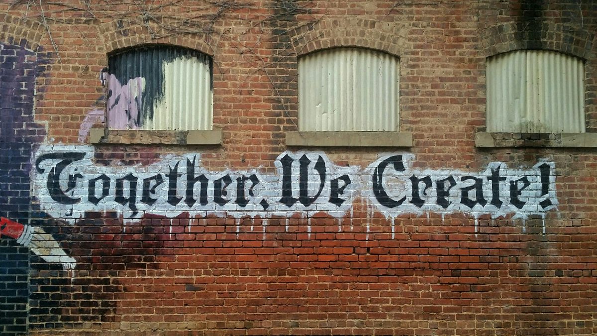 Brick wall with art that says 'together we create'