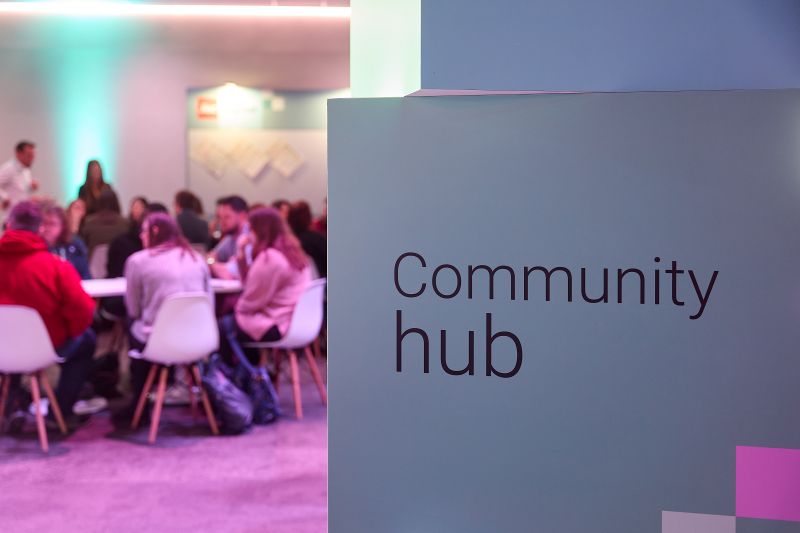 Sign with 'community hub' written in front of an area where people are participating in a workshop at Digifest 2026