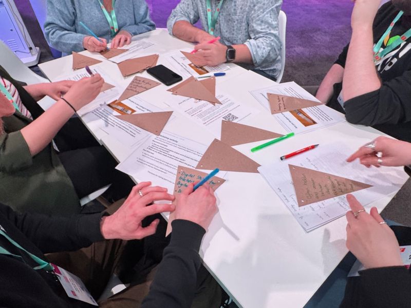 Image of people working at a table writing on banners to answer how their work in libraries is the 'glue work'