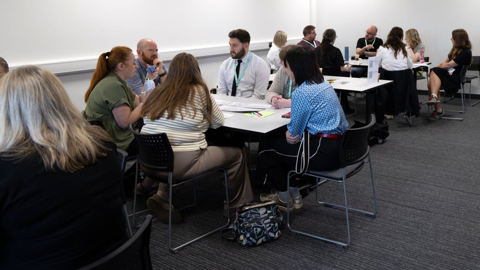 A large group of people discussing the recipe for success cards at the Powered by People event, 30 June 2026